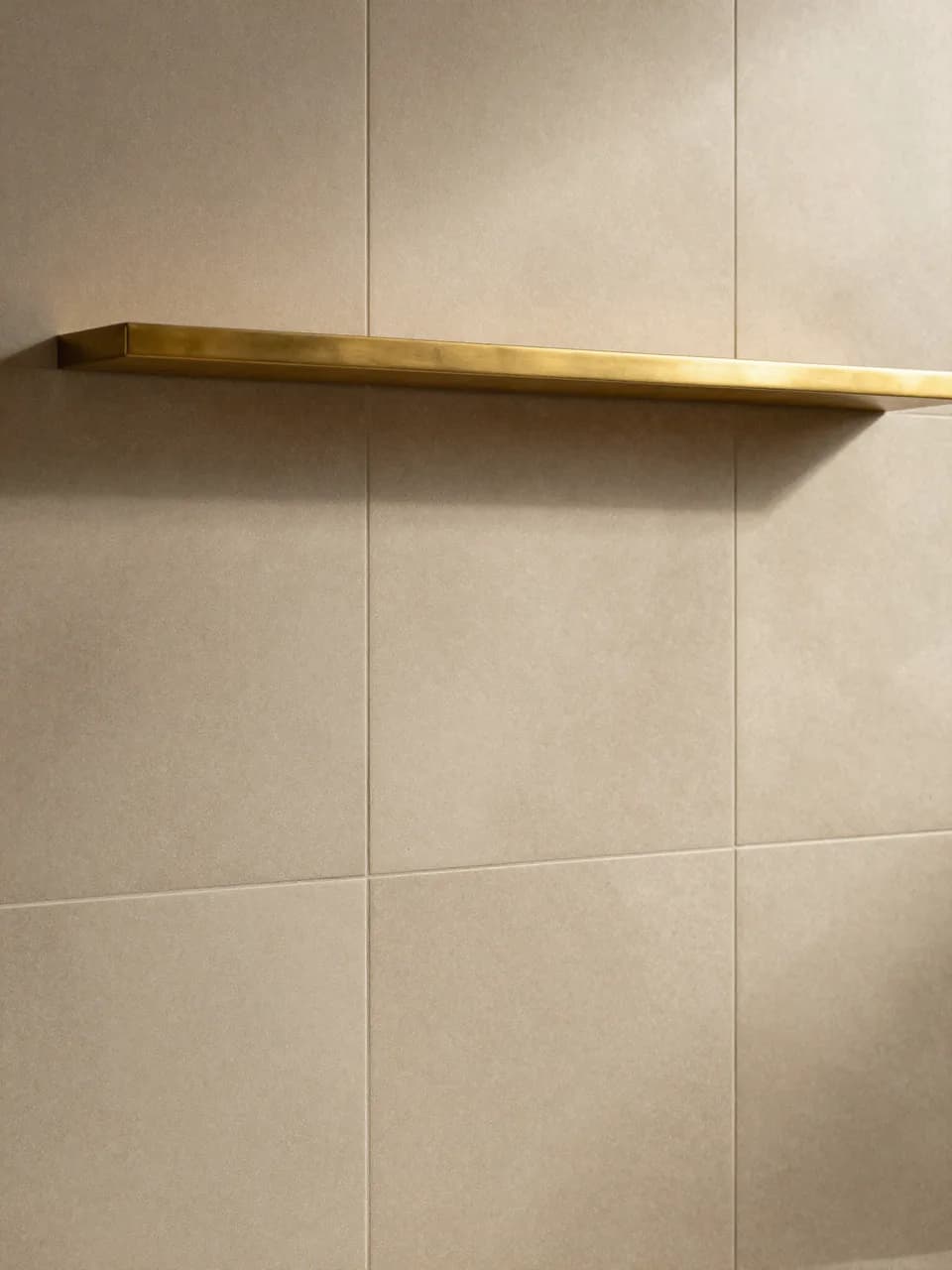 Herringbone marble flooring catching morning light beside a brass towel rail